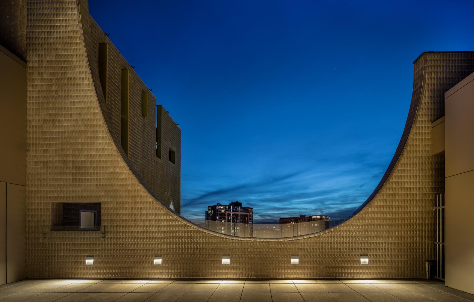 A scooped cut-out in a tiled wall reveals the twilight sky.