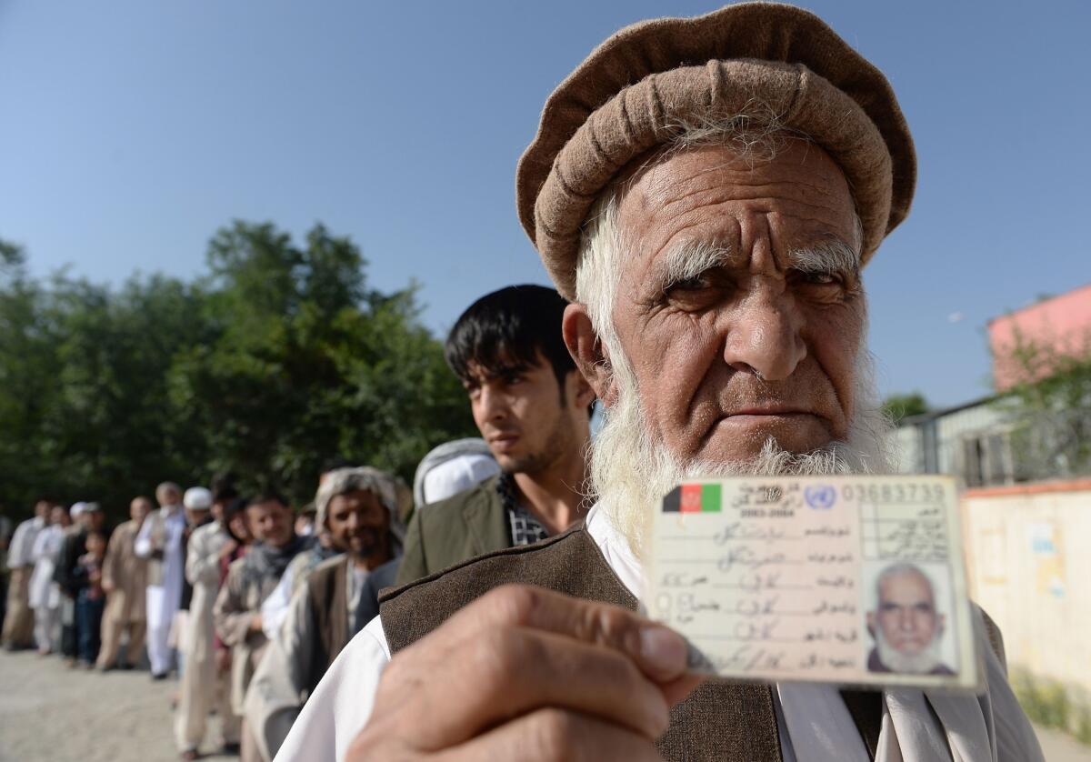 An Afghan resident poses for a photograph with his identification card as he waits for voting to start at a polling center in Kabul.