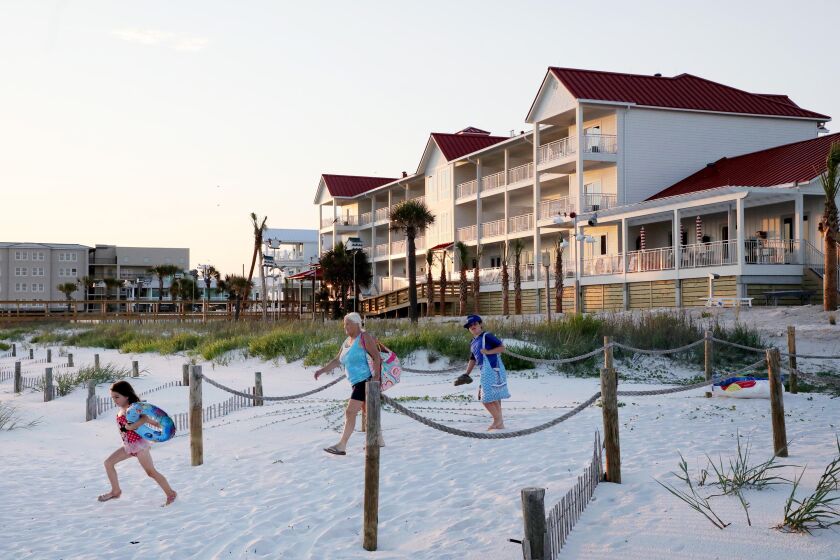 People arrive at Mexico Beach on Thursday, June 2, 2022, where one of its landmarks, the iconic Driftwood Inn, background, reopened nearly four years after it was destroyed by Hurricane Michael.
