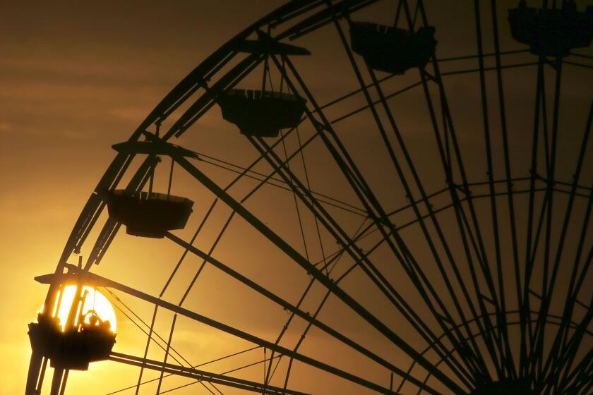 SANTA MONICA, CALIF. - OCT. 17, 2023. Visitors to Pacific Park are silhouetted against the setting sun at Santa Monica Pier on a recent afternoon. Warmer weather is expected throughout Southern California this week. (Luis Sincvo / Los Angeles Times) .
