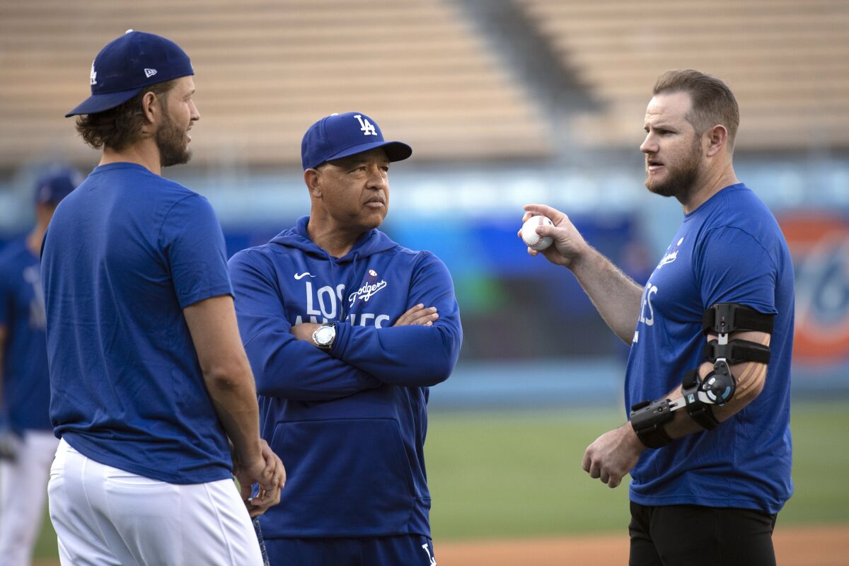 Dodgers infielder Max Muncy talks to manager Dave Roberts and pitcher Clayton Kershaw.