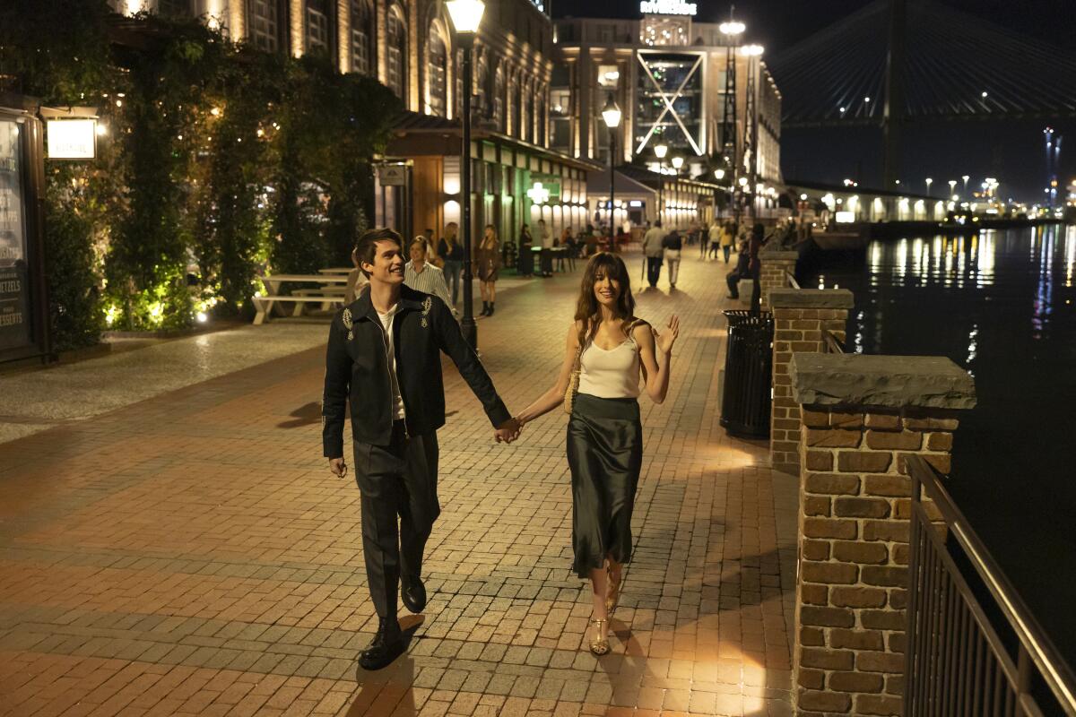 A man and a woman stroll on the street at night.