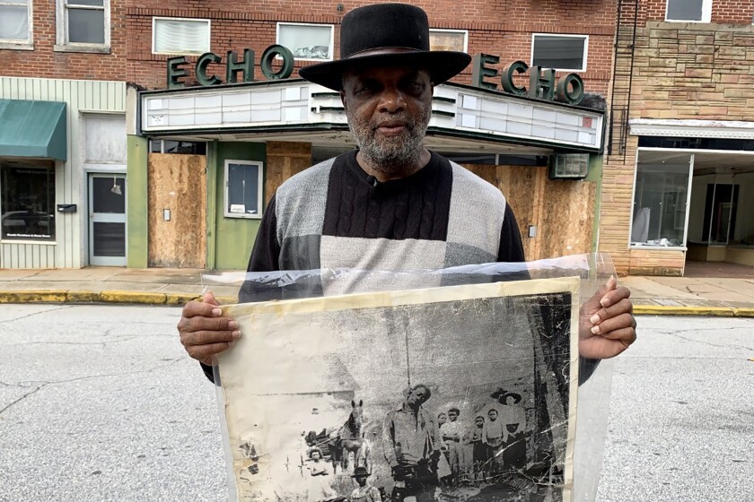 In this Monday, Jan. 13, 2020 photo, Rev. David Kennedy stands outside the Echo Theater holding a photo of his great uncle's lynching, in Laurens, S.C. Kennedy has fought for civil rights in South Carolina for decades. (AP Photo/Sarah Blake Morgan)