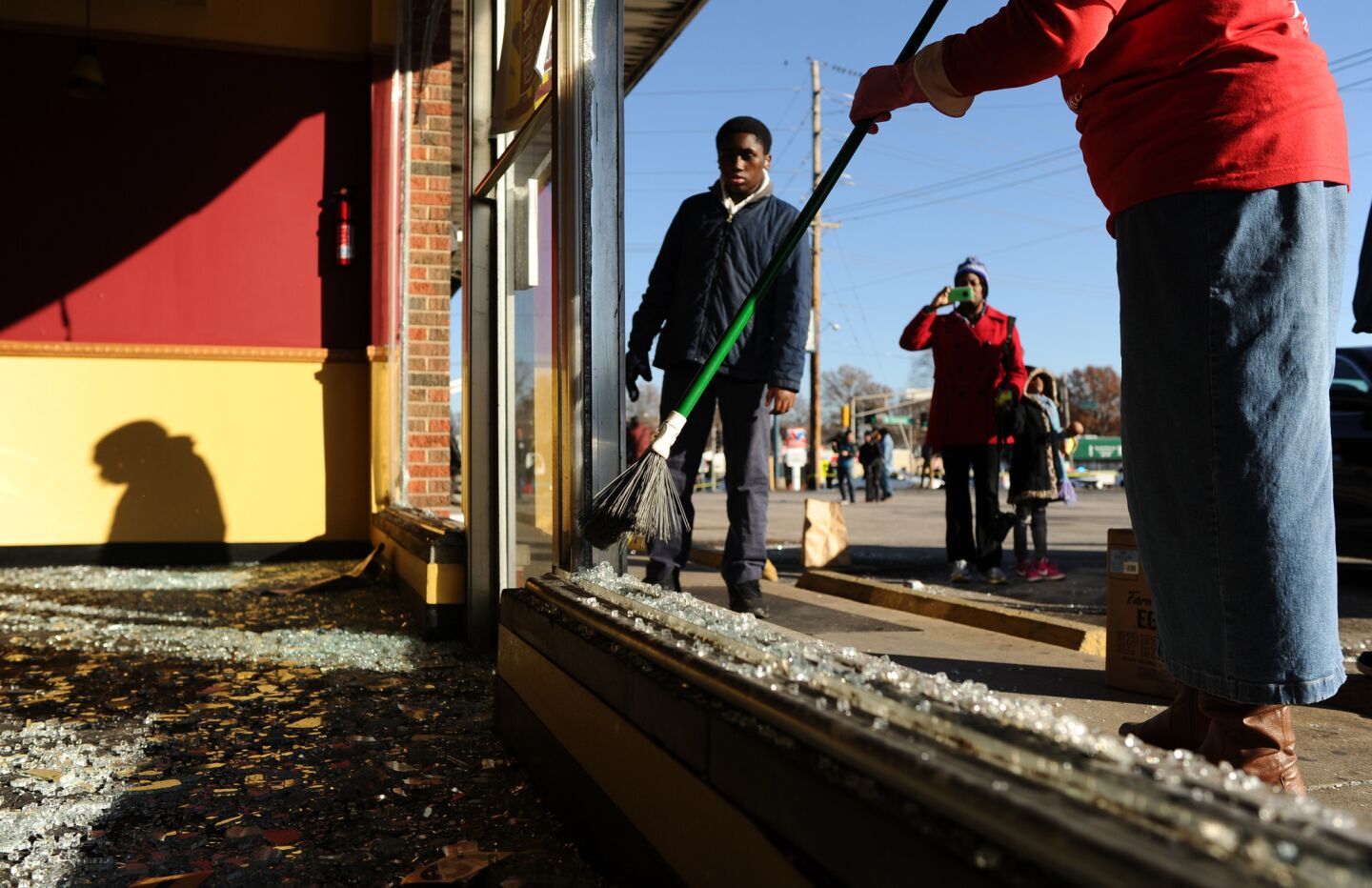 Volunteers clean up debris from a fire at a strip mall a day after rioting on Chambers Road and West Florissant Avenue in Ferguson, Mo.