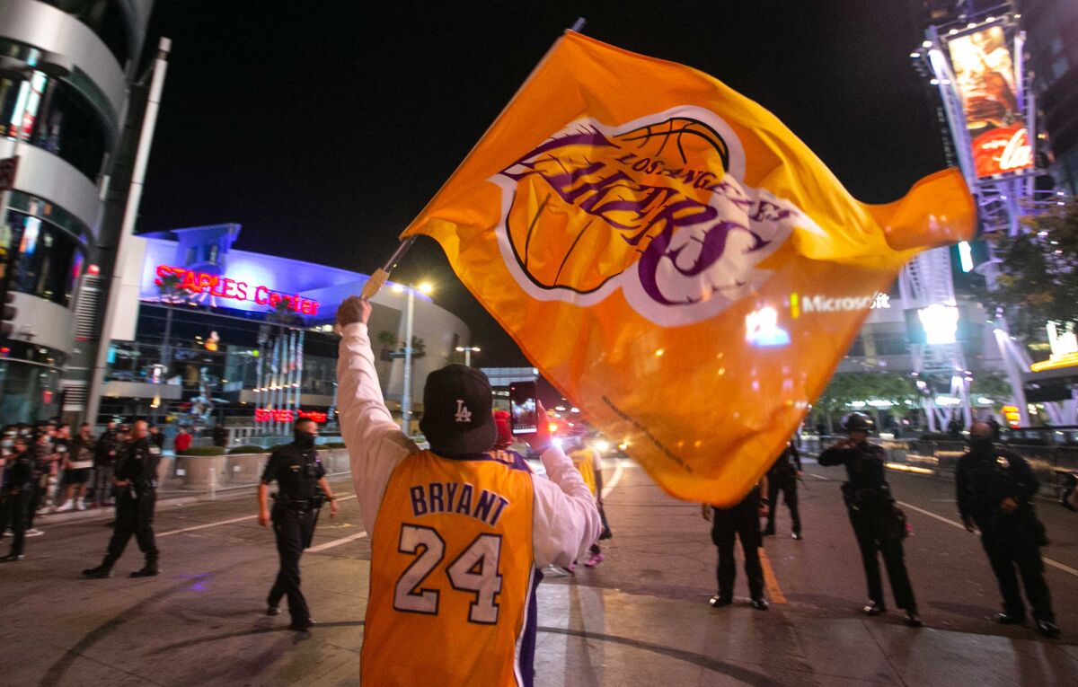 A fan in a Kobe Bryant jersey waves a Lakers flag in downtown Los Angeles after the team won the NBA championship Oct. 11