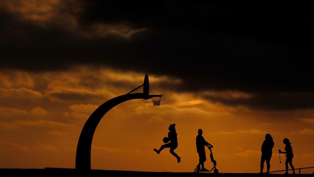 People are silhouetted against a golden sky in Angels Gate Park in Los Angeles on Aug. 23, 2018.