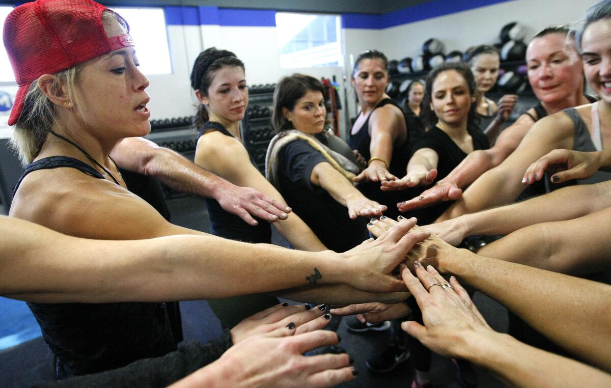 Fitness trainer Lacey Stone, left, joins hands with her students at the end of workout session.