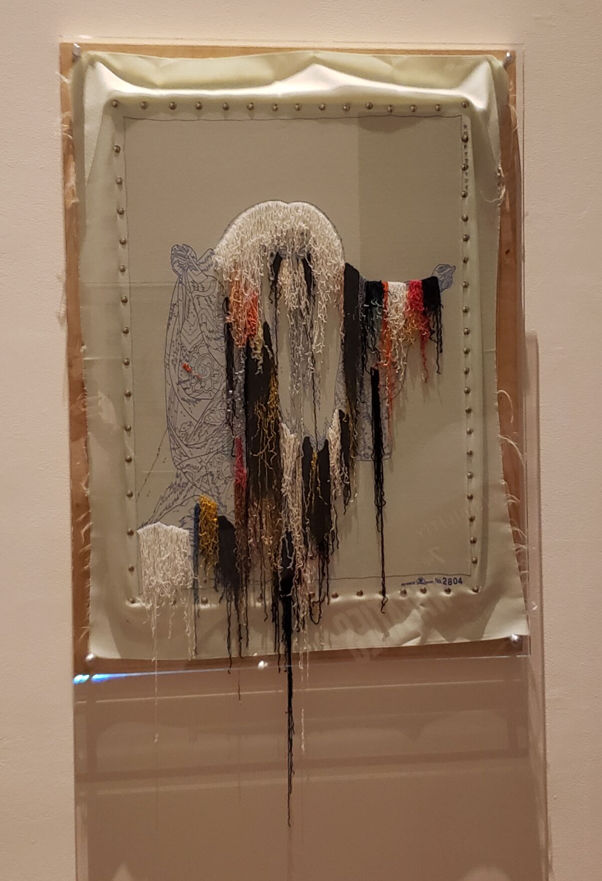 Colorful embroidery threads hang loose in Glenn Kaino's "Open Thread."