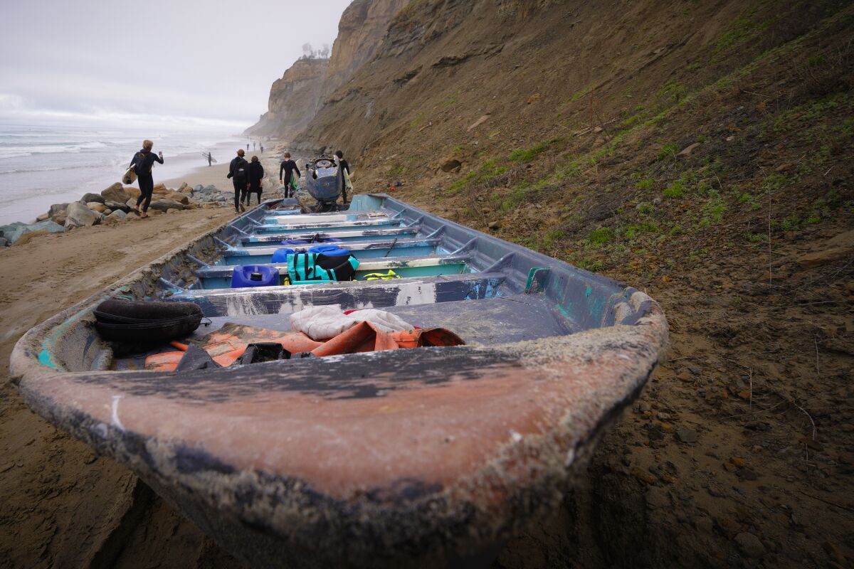 Beachgoers examining an abandoned boat with leftover life jackets
