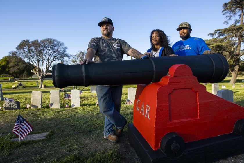 Compton, CA - February 27: Dan Walker, left, of Compton Veterans and Walker Family Events Foundation, Celestina Bishop, center, founder of nonprofit, One Section At A Time, and Sherman Watson, of Compton Veterans and The Mission Continues, stand next to a freshly-painted Civil War veteran's grave marker after joins One Section At A Time volunteers and fellow Compton Veterans volunteers installing a flag pole, cleaning up and beautifying Woodlawn Memorial Park Cemetery where about 450 veterans are buried Saturday, Feb. 27, 2021 in Compton, CA. Celestina Bishop, founder of nonprofit, One Section At A Time, which is dedicated to rebuilding Woodlawn, is trying to take over Woodlawn Memorial Park Cemetery in Compton, which was abandoned a few years ago. She started One Section at a Time to clean the neglected cemetery. Bishop then contacted the owner of the cemetery who told her, he couldn't afford to maintain that property and owes more than $820,0000 in back taxes. Celestina and her husband, Mr. Jackson, have used about $220,000 of their savings to install an irrigation system and improve the cemetery. "My family was bludgeoned to death. They found me two days later," Bishop said. Bishop said she used to sleep in front of her mother and sisters' graves with her grandmother at the cemetery. "Home is where the heart is and this is my home." (Allen J. Schaben / Los Angeles Times)