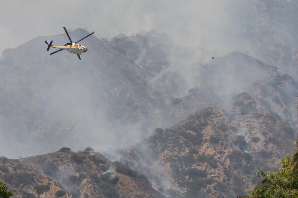 A helicopter helps to douse a fire near Brand Park in Glendale Sunday afternoon