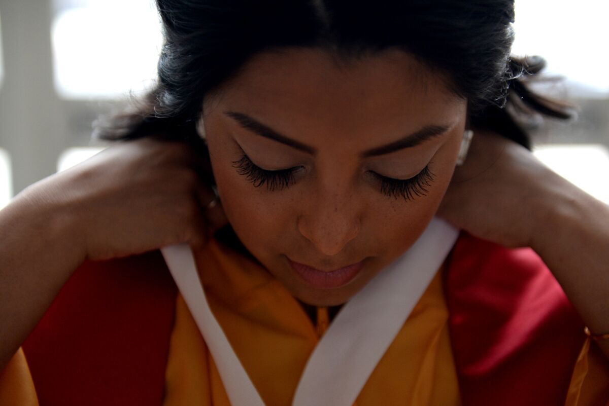 Shari Martinez puts on her gown before the Thomas Riley High School graduation. (Callaghan O'Hare / Los Angeles Times)