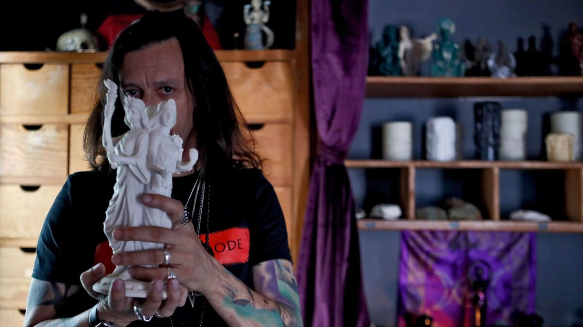 Occultist Sal Santoro, owner of the Crooked Path, an occult apothecary store, shows a statue of Hecate, at his store on Magnolia Avenue in Burbank on Friday. Santoro invites everyone to come in and look around the store, ask questions and learn about the items.