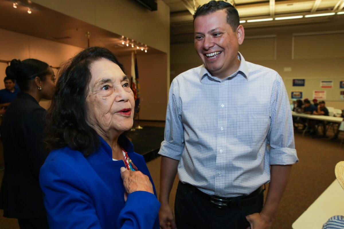 Rudy Salas, standing with Dolores Huerta, smiles as she speaks