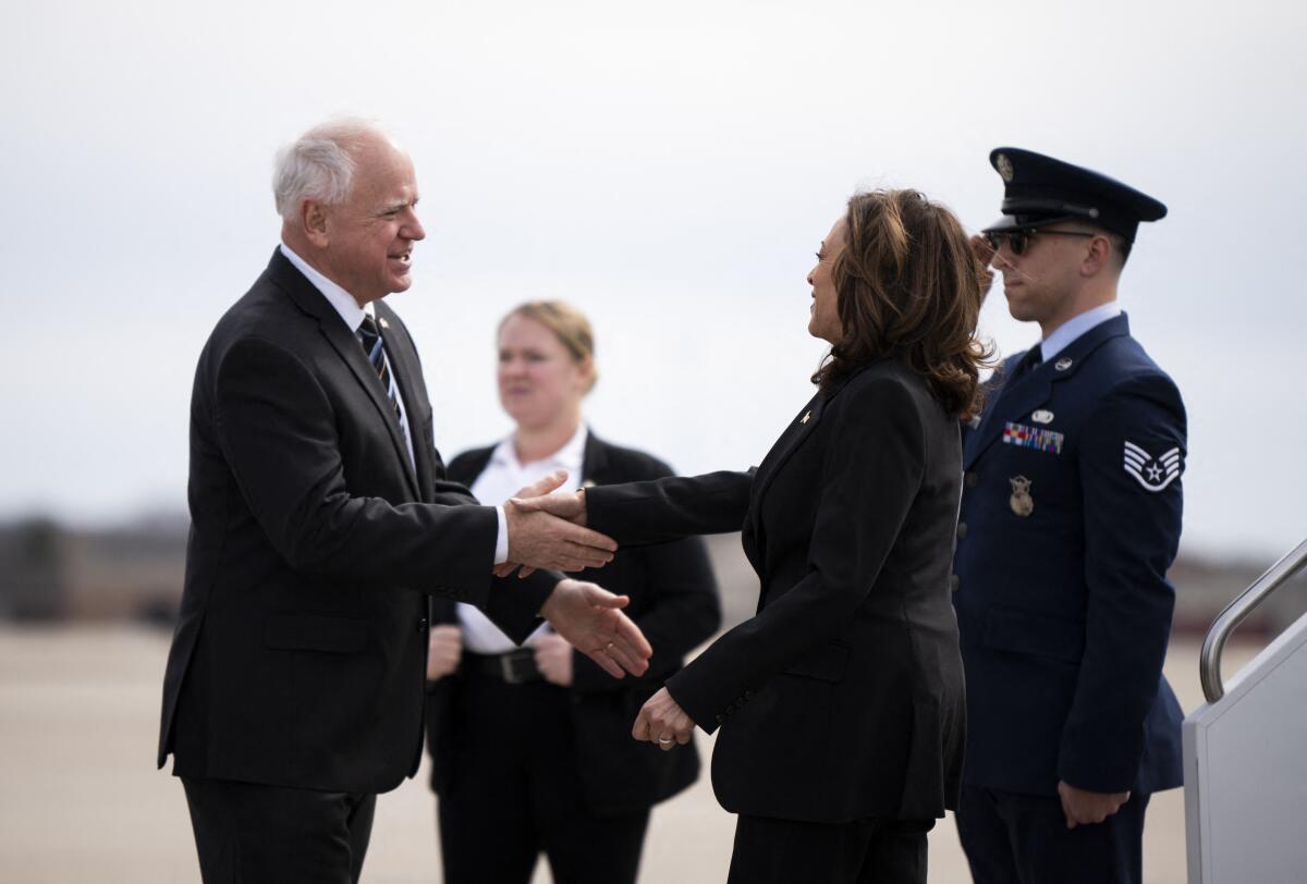 Tim Walz and Kamala Harris shake hands at an airport.