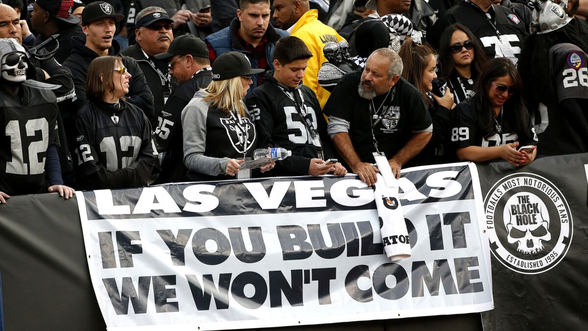 Oakland Raiders fans stand behind a sign in advance of the team's decision to move to Las Vegas.