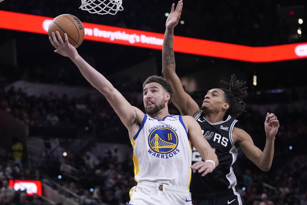 Warriors guard Klay Thompson gets past Spurs guard Devin Vassell, right, during a game in March.