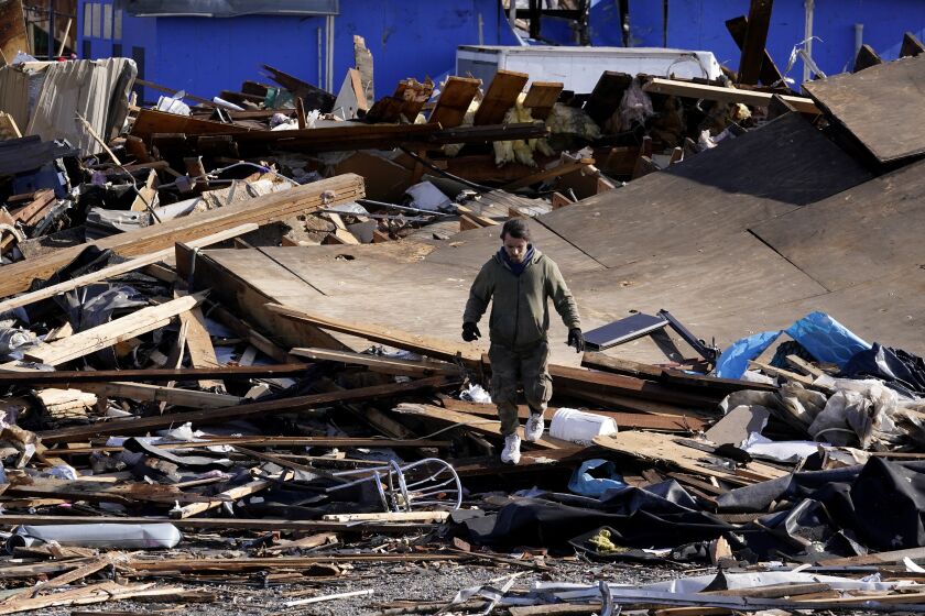A person walks through debris and damage from a tornado in Mayfield, Ky., on Saturday, Dec. 11, 2021. Tornadoes and severe weather caused catastrophic damage across multiple states Friday, killing multiple people overnight. (AP Photo/Mark Humphrey)