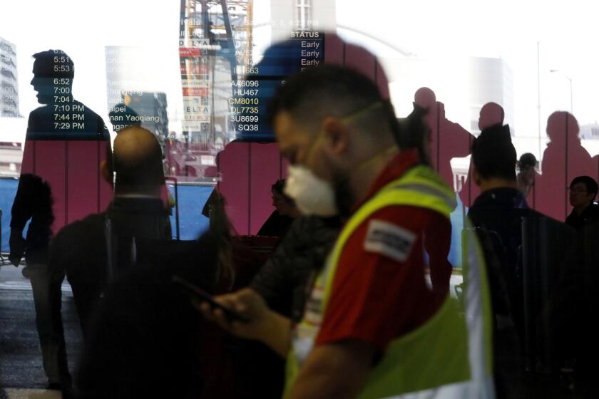 An LAX worker wears a mask amid fears of coronavirus at the Tom Bradley International Terminal at Los Angeles International Airport on Feb. 8