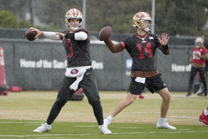 San Francisco quarterbacks Brock Purdy (13) and Sam Darnold (14) work out side by side in practice.