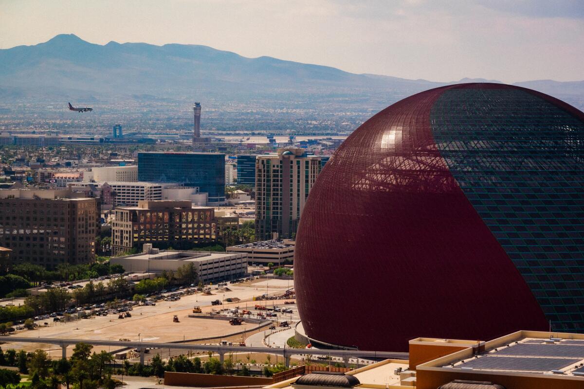 A view of a spherical building against the Las Vegas cityscape on a bright, sunny day.