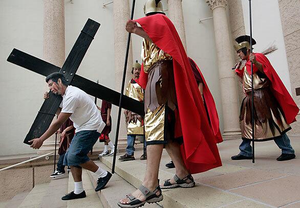 Seven churches from East L.A. have joined forces for the first time to stage an elaborate re-enactment of the Stations of the Cross for Palm Sunday. Simon Mares (left, as Jesus carrying the cross) and other cast members rehearse recently at Calvary Cemetery.