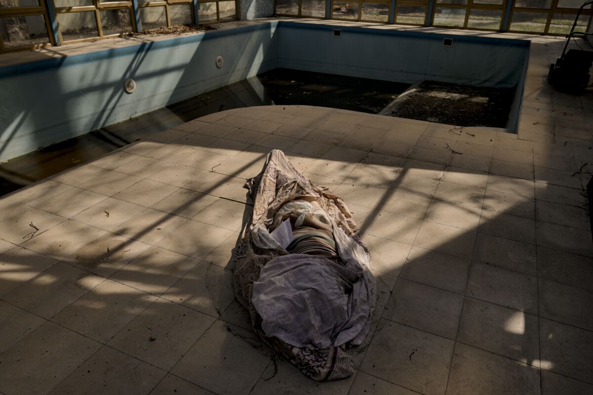 A body wrapped in fabric on the ground beside a swimming pool