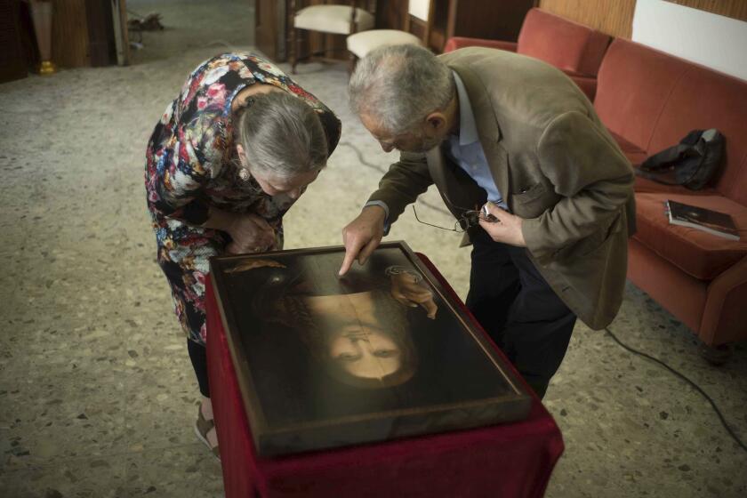 This image released by Sony Pictures Classics shows Dianne Modestini, left, and Ashok Roy inspecting the Naples copy of the Salvator Mundi in a scene from "The Lost Leonardo." (Adam Jandrup/Sony Pictures Classics via AP)