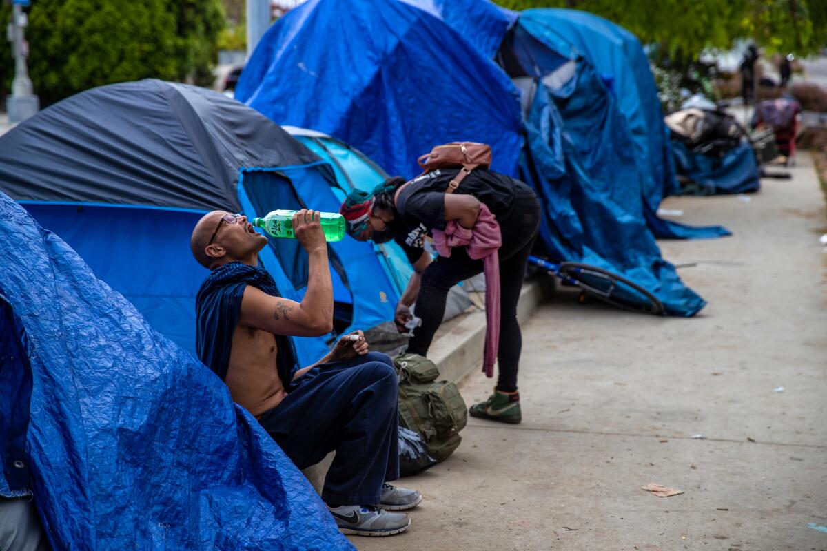 Residents of a homeless encampment outside their tents on Venice Boulevard in Los Angeles.