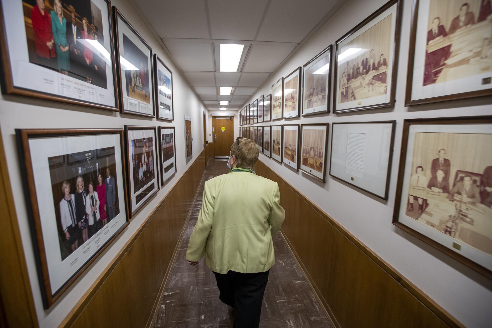 Kuehl walks down a long hallway lined with framed photos.