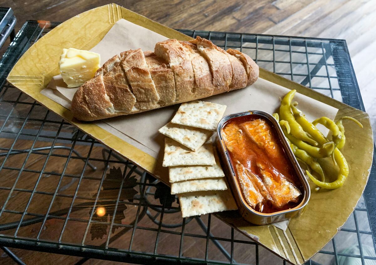 Tinned fish and sliced bread on a platter with crackers at Kippered.