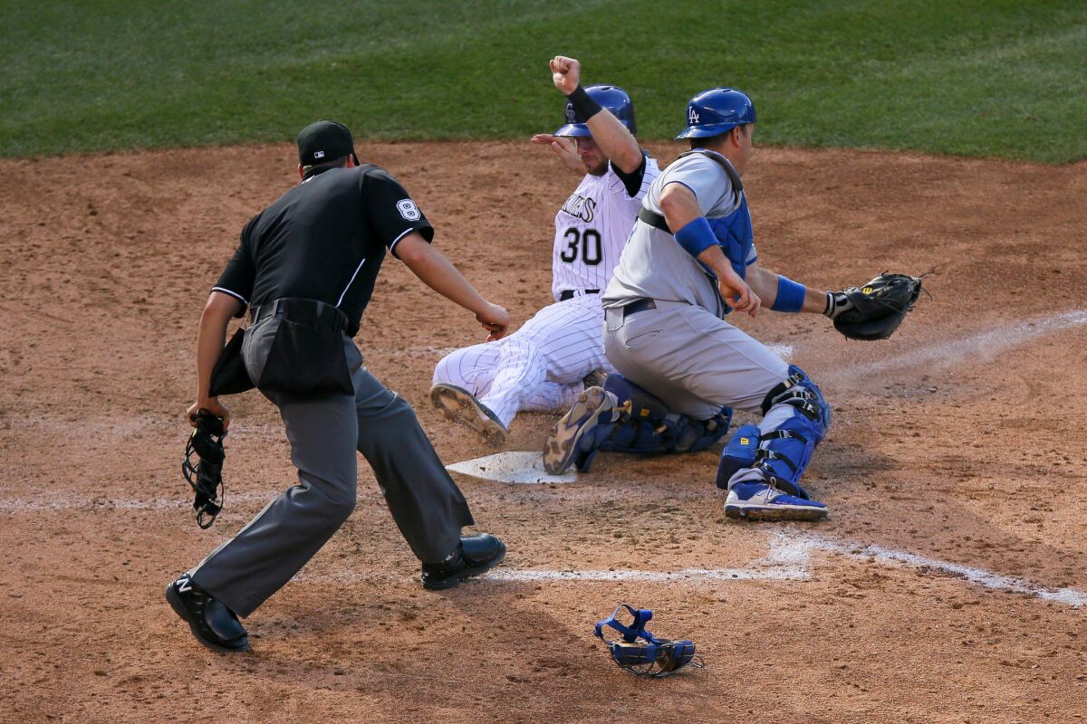 Rockies catcher Tom Murphy slides in safely to score on a suicide squeeze ahead of the tag by A.J. Ellis.