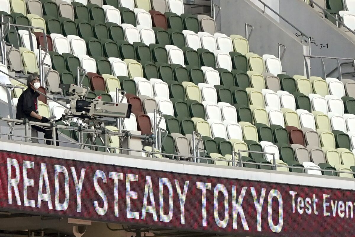 A TV cameraman sits beside empty spectators' seats during an athletics test event for Tokyo 2020 Olympics Games at the National Stadium, in Tokyo, Japan, Sunday, May 9, 2021. Tens of thousands of visiting athletes, officials and media are descending on Japan for a Summer Olympics unlike any other. There will be no foreign fans, no local fans in Tokyo-area venues. A surge of virus cases has led to yet another state of emergency. (AP Photo/Shuji Kajiyama)
