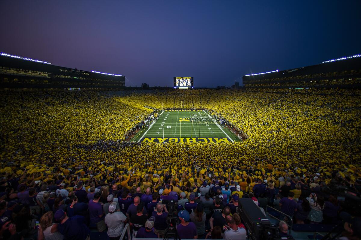 The Michigan Marching Band takes the field to a "maize out" crowd at Michigan Stadium.