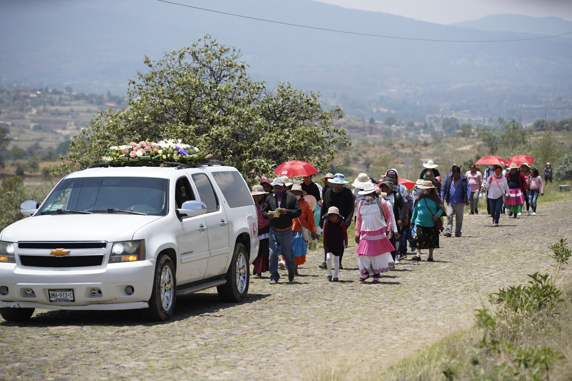 Familiares cantan canciones mientras caminan detrás del coche fúnebre que lleva a María Eugenia Chávez Segovia 