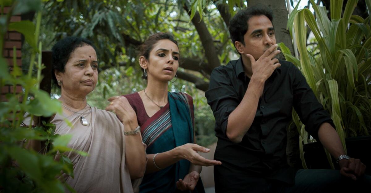 Two women and a man amid foliage in the movie “Peepal Tree.”