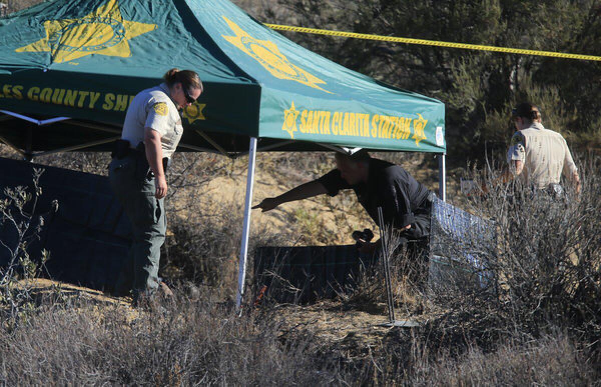 Investigators gather evidence at the scene off Lake Hughes Road near Castaic Lake where a burning body was discovered early Wednesday morning.