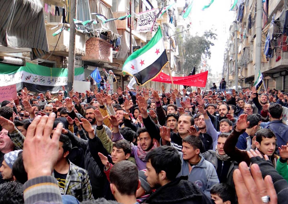 An amateur photo shows protesters holding Syrian revolution flags during a demonstration against the Syrian regime in Aleppo.