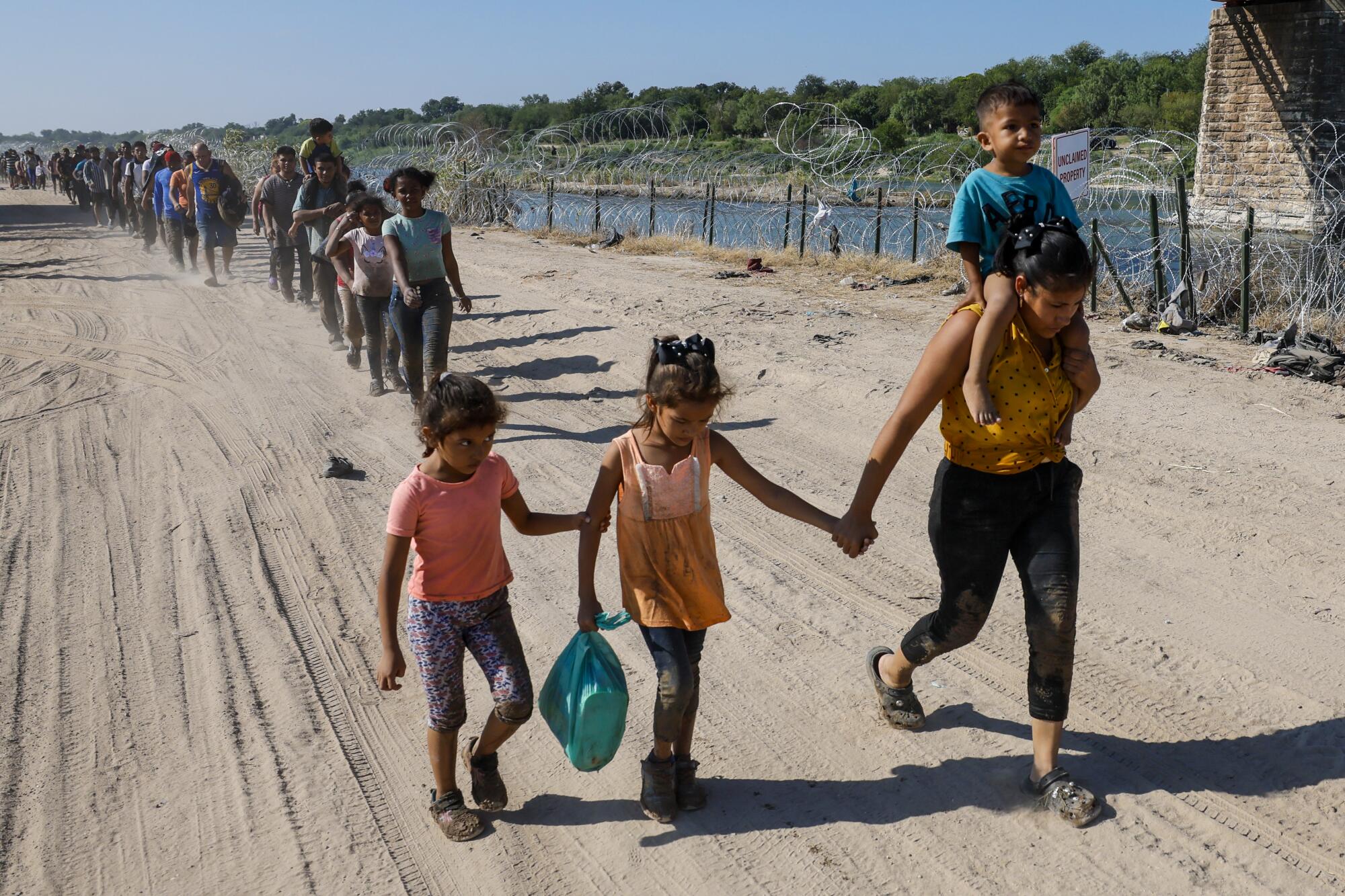 Hundreds of migrants walk to a U.S. Border Patrol staging area to be