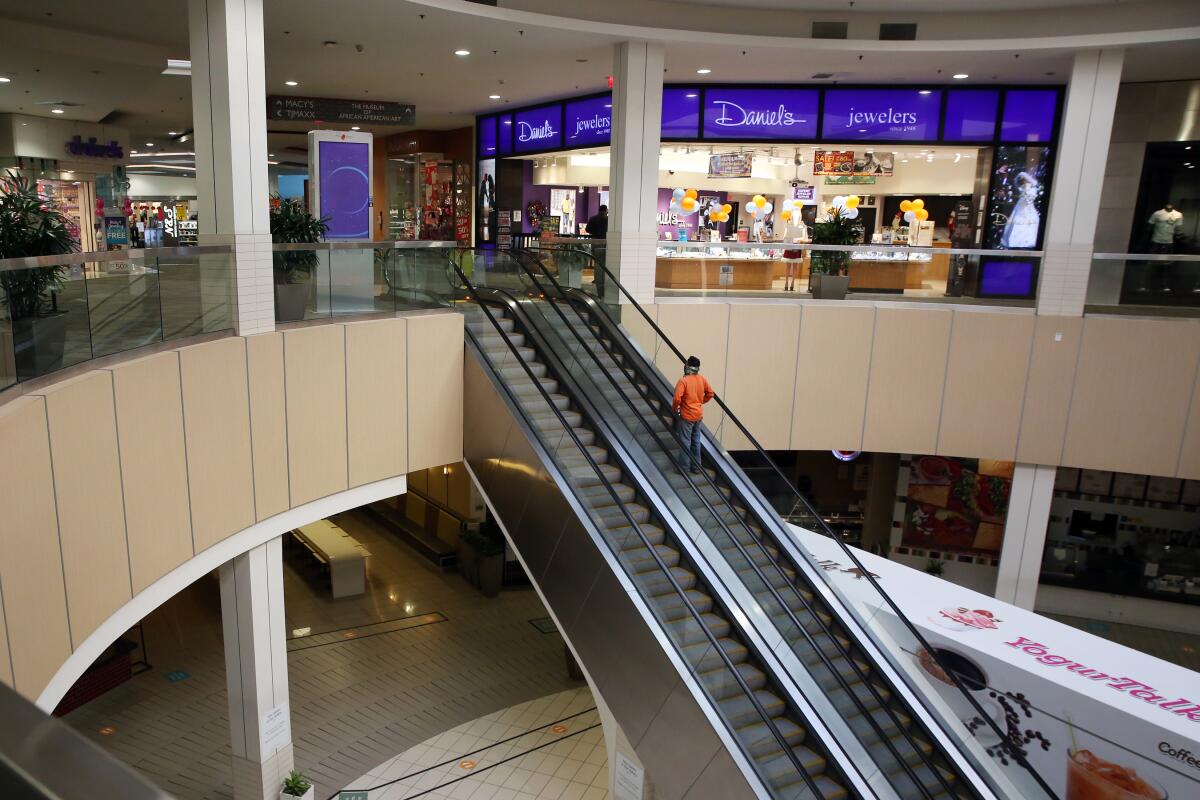 A person rides an escalator at a mall.
