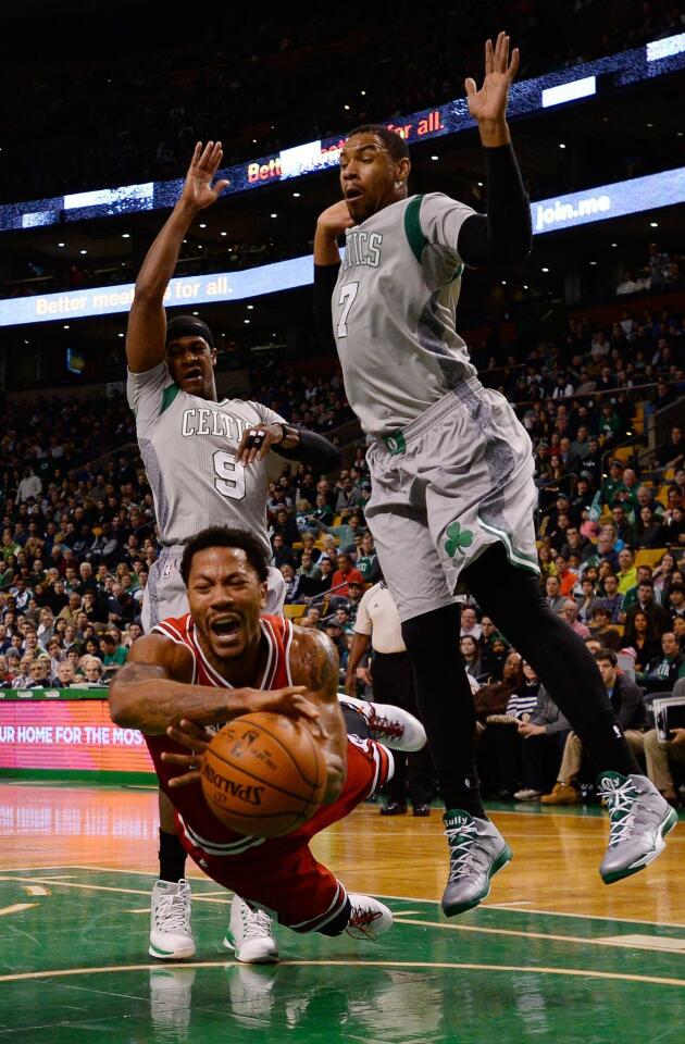Derrick Rose gets tripped up as Celtics guard Rajon Rondo (9) and forward Jared Sullinger defend during the first half.