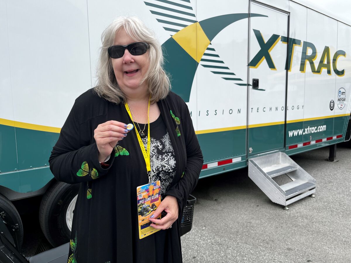 IndyCar superfan Kathy Burgemeister smiles while standing between race trailers at the Long Beach Grand Prix
