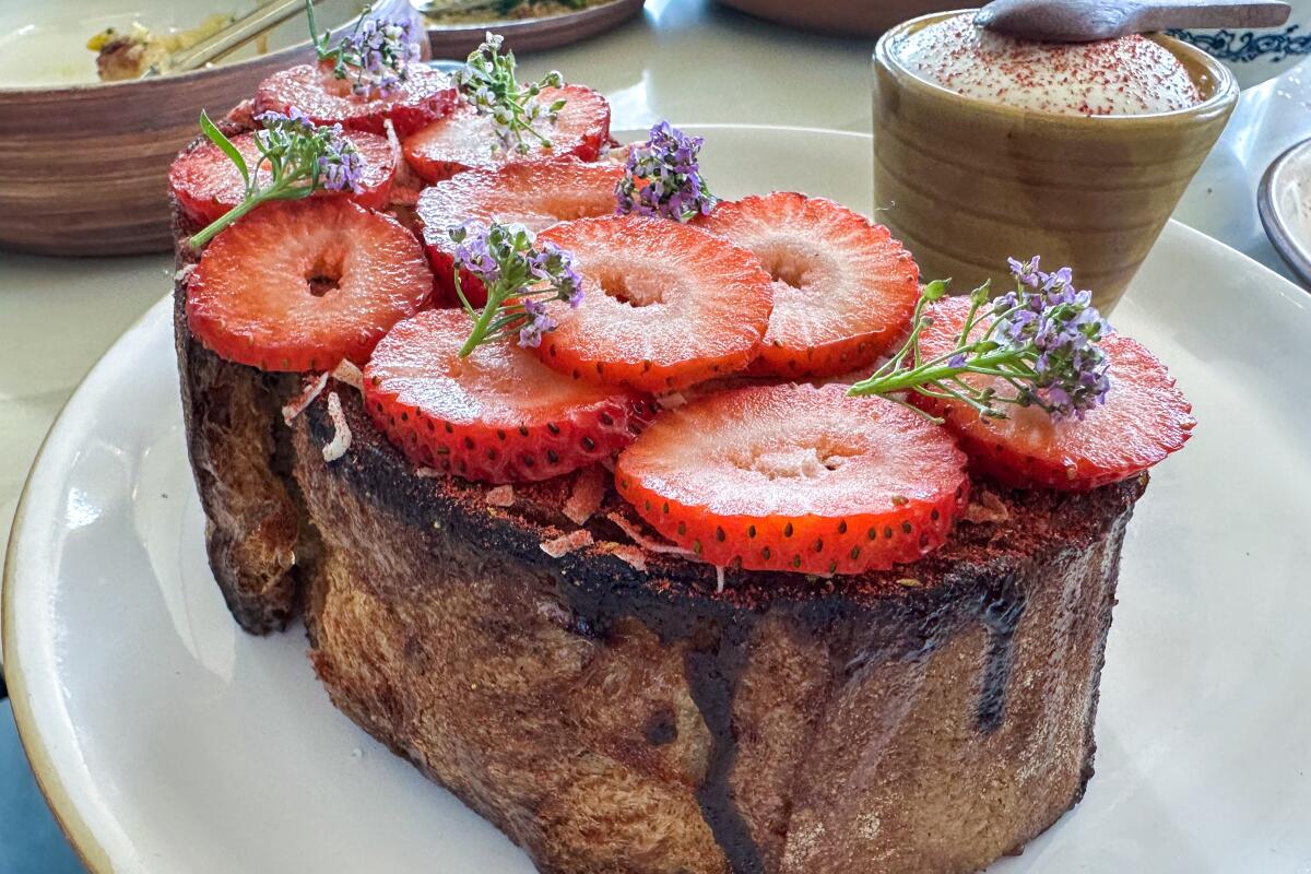 French toast, soaked in custard and crowned with strawberries, decorated with small purple flowers