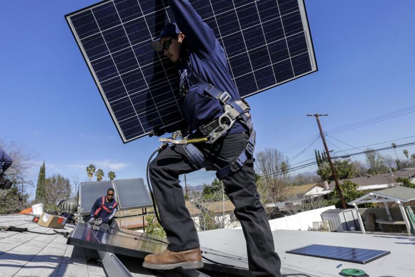 VAN NUYS, CA FEBRUARY 04, 2016 -- Alejandro DeLeon carries a solar panel as crew from Sunrun home solar company instal a solar system on home in Van Nuys. (Irfan Khan / Los Angeles Times)