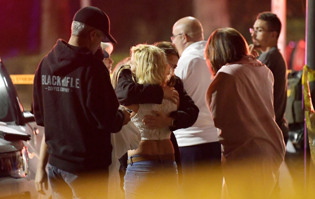 FILE - In this Nov. 8, 2018, file photo, people comfort each other as they stand near the scene of a shooting in Thousand Oaks, Calif., where a gunman opened fire inside a country dance bar crowded with hundreds of people. Video released Tuesday, Jan. 18, 2022, from body cameras worn by deputies who responded to the mass shooting captures the chaos deputies encountered when they arrived at the scene. The video was released after a court fight by The Associated Press and other news outlets to have the video released. (AP Photo/Mark J. Terrill, File)