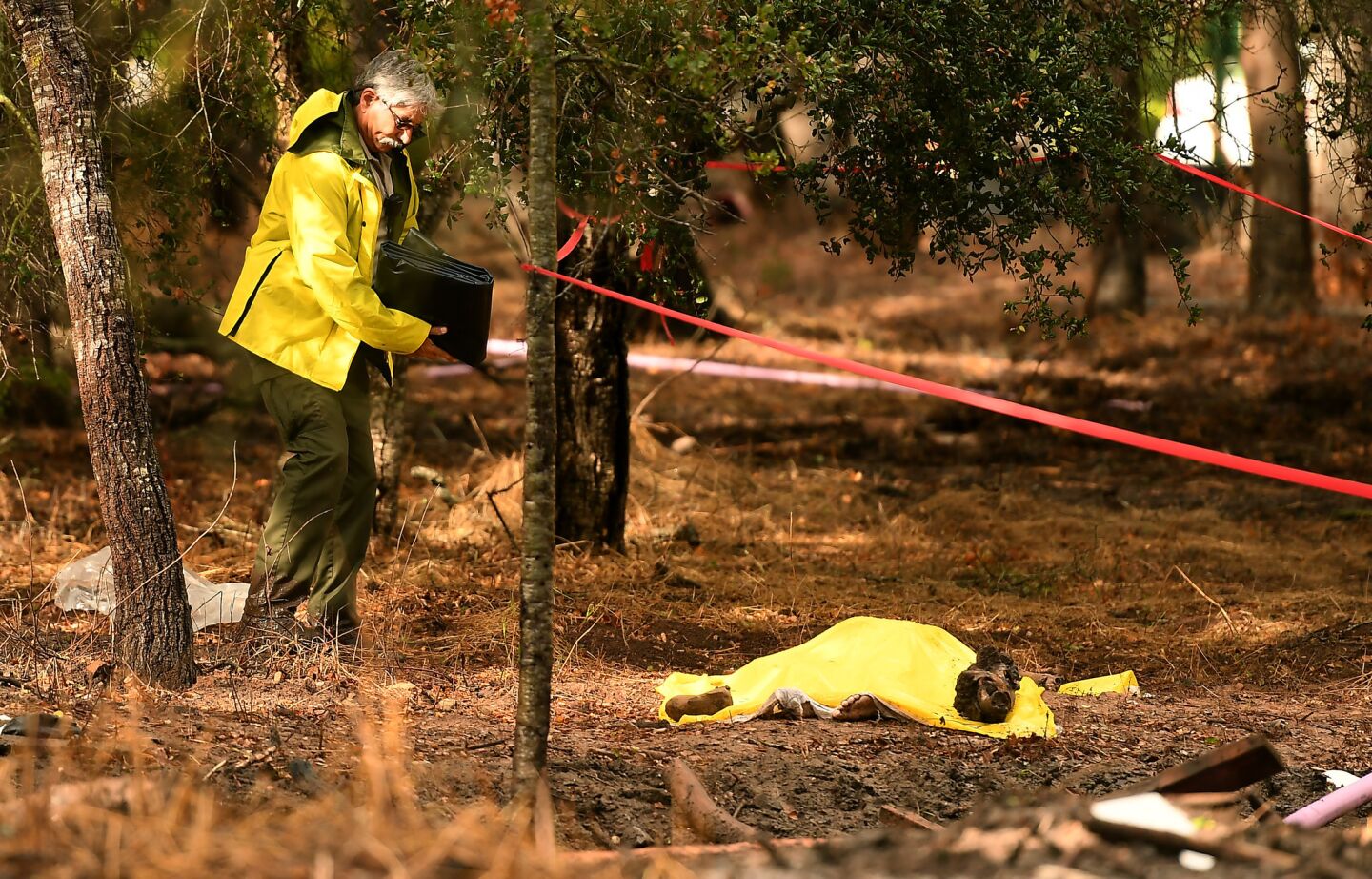 A sheriffs deputy stands near a body covered by a tarp near Hot Springs Road in Montecito after a deadly mudslide swept through the area.