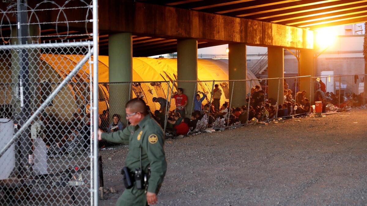 Migrants are huddled in a holding pen last year beneath a bridge at the El Paso crossing.