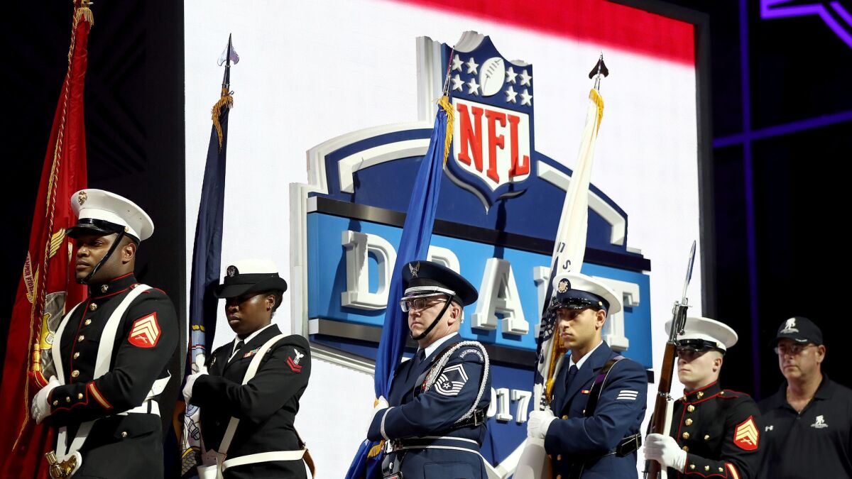 A military color guard marches to the stage before the start of the NFL draft.