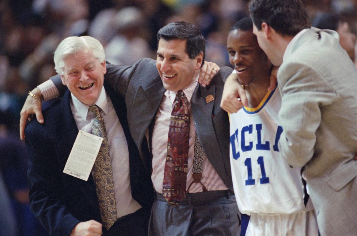 UCLA coach Jim Harrick, center, gets a hug from associate athletic director Jim Milhorn as guard Tyus Edney (11) is congratulated after the Bruins eliminated Connecticut in the NCAA West Regional championship March 25, 1995, in Oakland.