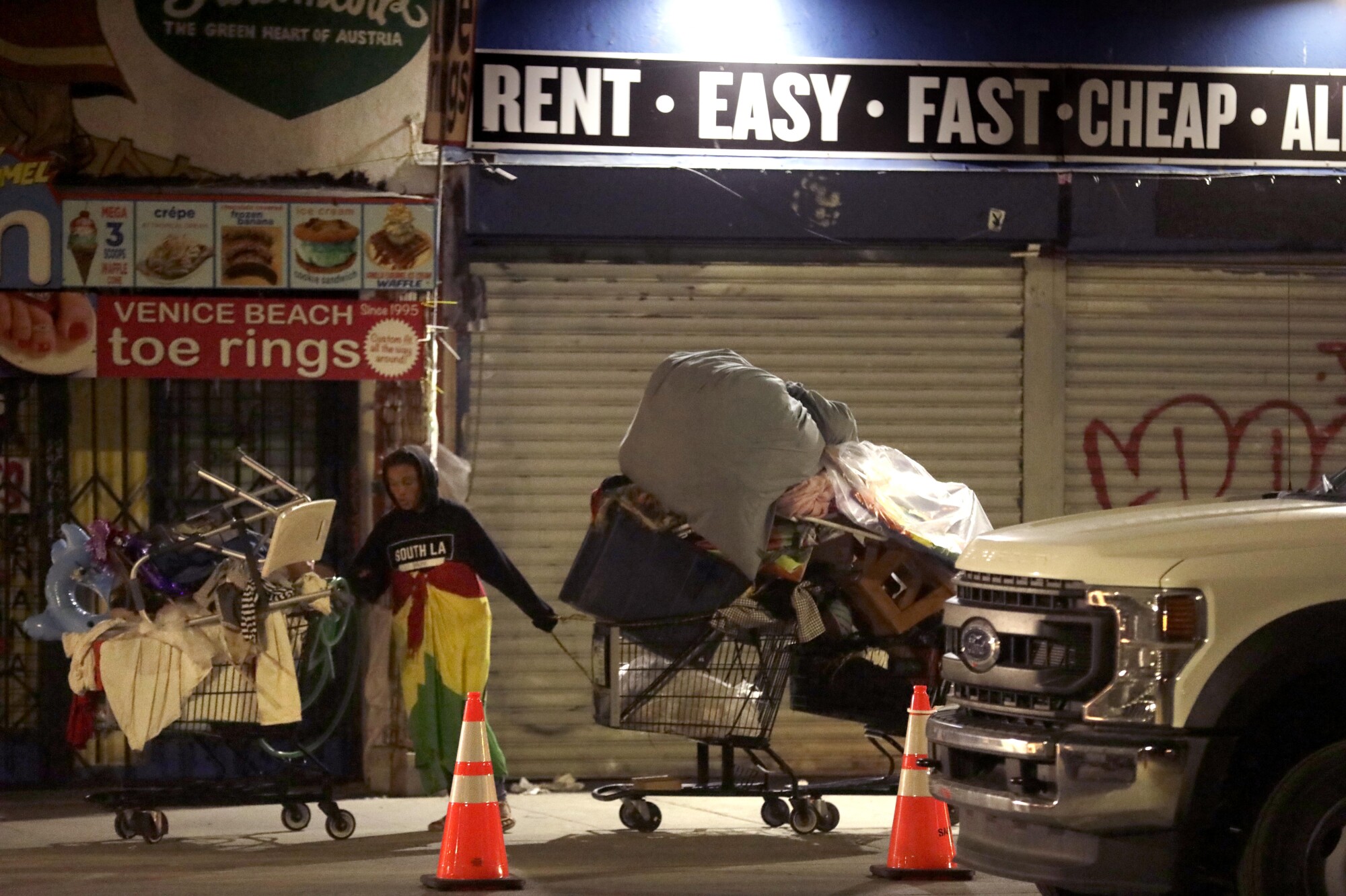 A homeless woman pulls her belongings after LAPD officers asked her to leave her encampment in Venice.